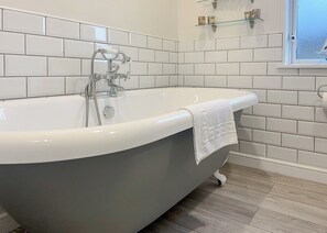 Ein modernes Badezimmer mit freistehender Badewanne, weißen Fliesen und Holzboden.