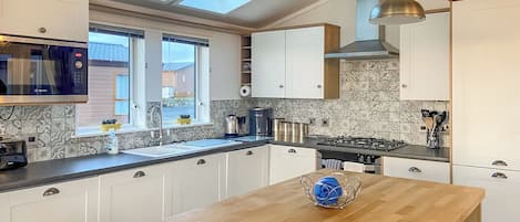 A modern kitchen with a skylight, a Bosch microwave, a coffee maker, and a wooden dining table.