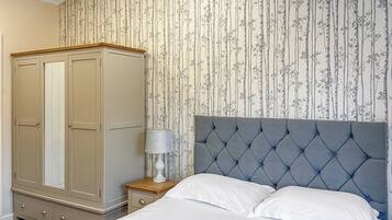 A bedroom with a bed, a wardrobe, a nightstand, and a lamp.