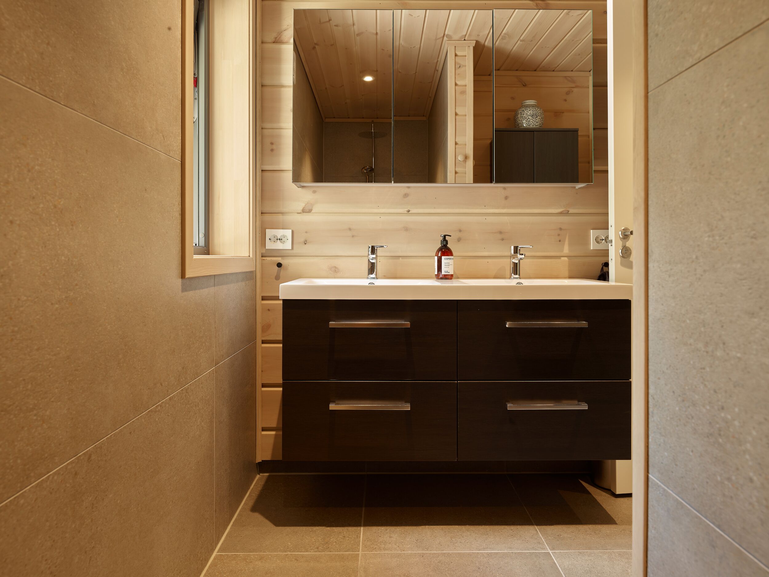 A modern bathroom with a wooden vanity, two sinks, and a large mirror.