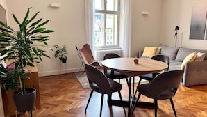 A modern living room with a round wooden table, two chairs, a sofa, and a potted plant. - Riverside Apartment Ljubljana with free parking (Ljubljana)