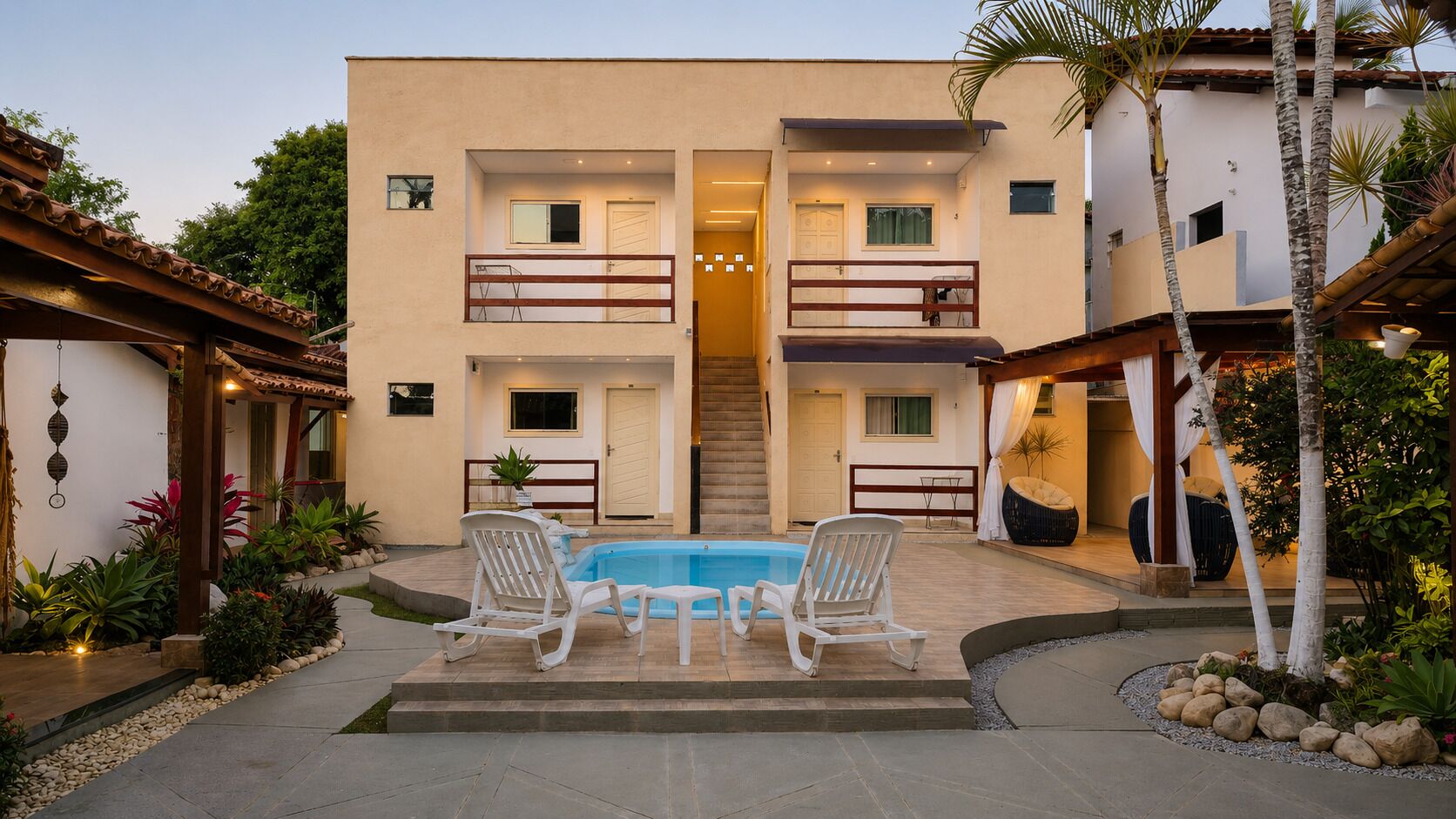 Um edifício de dois andares com piscina, área de estar externa e um terraço coberto.
