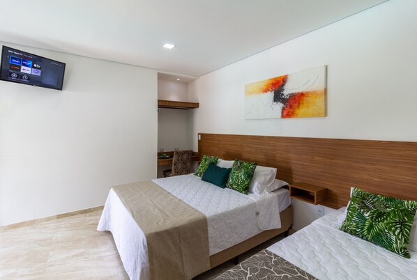 Une chambre d’hôtel avec un lit, un téléviseur fixé au mur et un tableau au-dessus du lit.