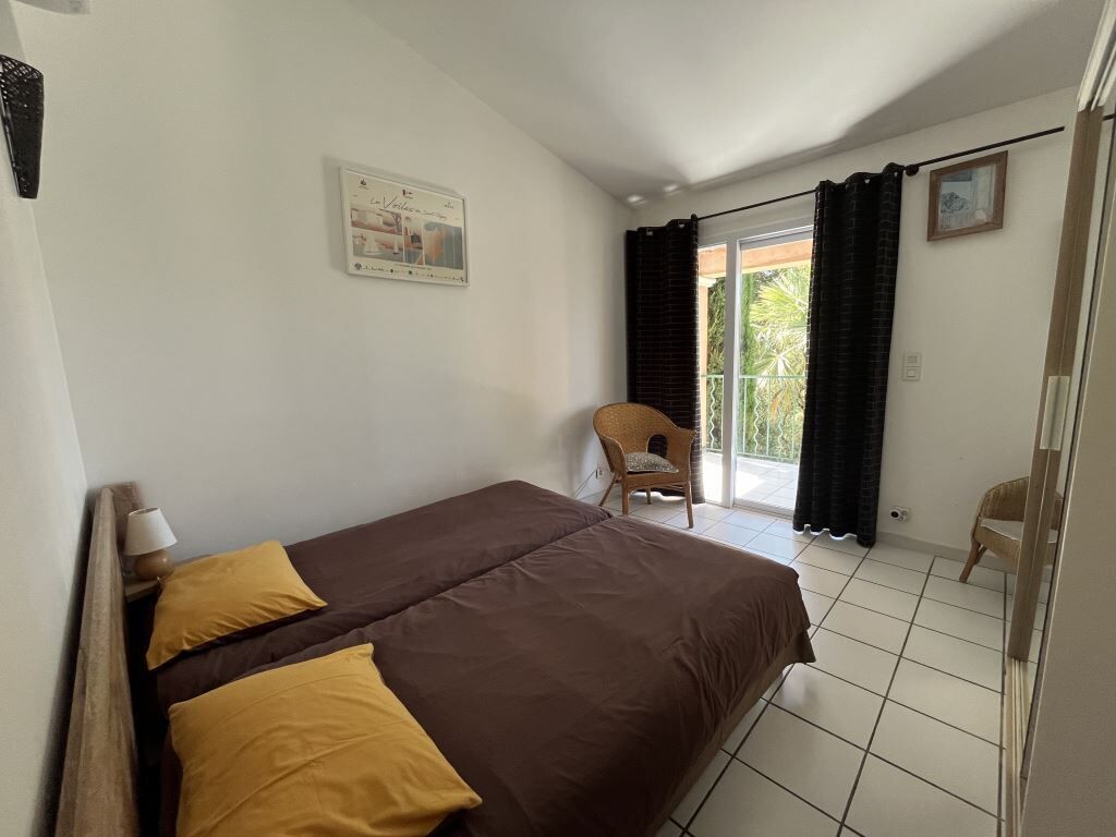 A bedroom with a bed, a chair, and a window with curtains.