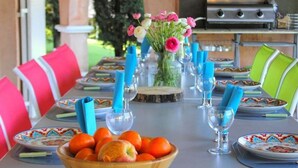 A dining table set with plates, glasses, and a bowl of fruit. - Villa, (14 p), panoramic view of the hills. Large infinity pool.  (Le Plan-de-la-Tour)