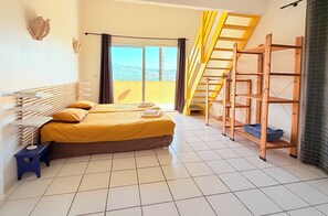 A hotel room with a bed, a small stool, a wooden shelf, and a view of the outdoors. - Villa, (14 p), panoramic view of the hills. Large infinity pool.  (Le Plan-de-la-Tour)