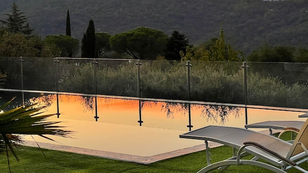 A poolside area with a view of a mountainous landscape during sunset. - Villa, (14 p), panoramic view of the hills. Large infinity pool.  (Le Plan-de-la-Tour)