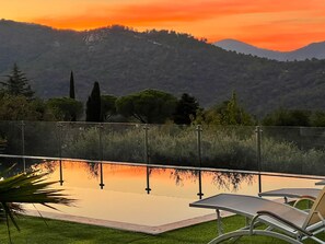 A poolside area with a view of a mountainous landscape during sunset. - Villa, (14 p), panoramic view of the hills. Large infinity pool.  (Le Plan-de-la-Tour)