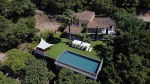 An aerial view of a property with a swimming pool, a covered patio area, and a house surrounded by trees. - Villa, (14 p), panoramic view of the hills. Large infinity pool.  (Le Plan-de-la-Tour)