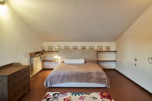 Une chambre à coucher comprenant un lit, une commode, une table de chevet et une étagère murale ornée de tableaux.