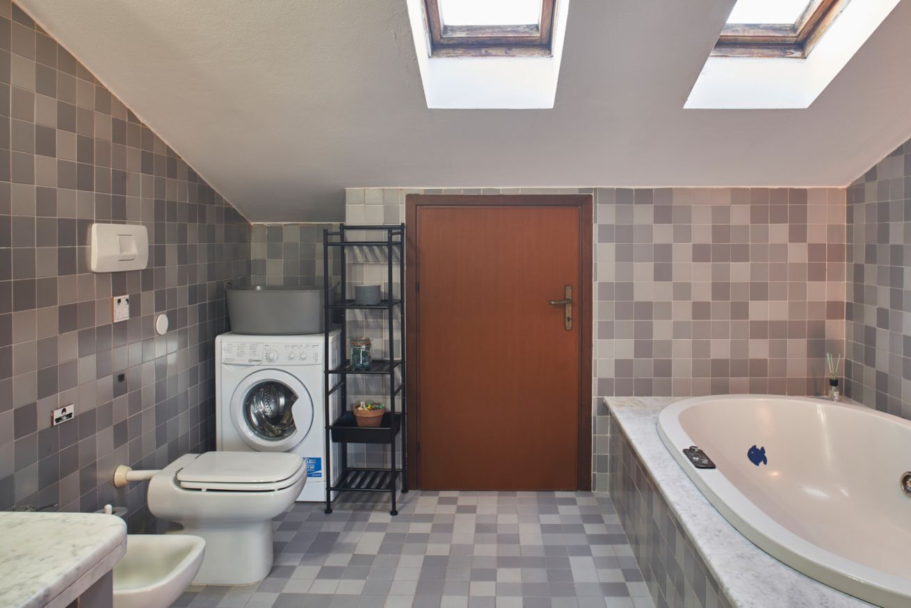 Une petite salle de bain équipée d’un lave-linge, de toilettes et d’une baignoire.