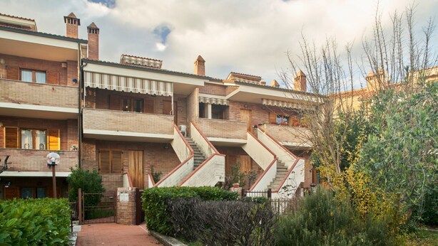 Un edificio residencial con varios balcones, fachada de ladrillo y una escalera central.
