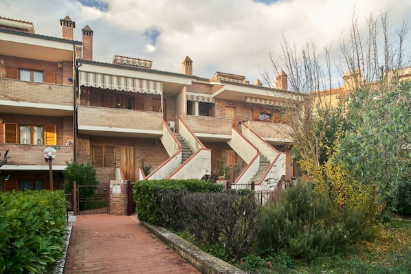 A residential building with multiple balconies, a brick facade, and a central staircase.