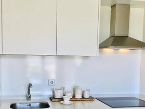 A kitchen with a stainless steel sink, a modern range hood, and a countertop with a coffee maker and cups. - Diamond Suite Luxury Penthouse (Granada)