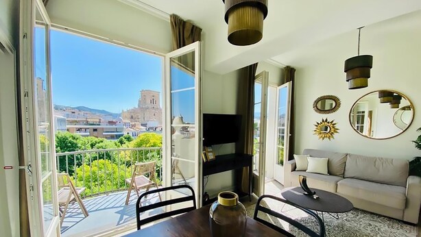 A room with a balcony, a sofa, a TV, and a table with a vase. - Diamond Suite Luxury Penthouse (Granada)