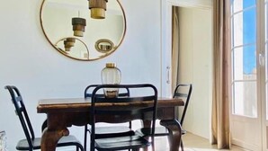 A dining area with a wooden table and four chairs, a round mirror on the wall, and a vase on the table. - Diamond Suite Luxury Penthouse (Granada)