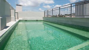 A rooftop swimming pool with clear blue water, surrounded by a white pool deck and a metal railing. - Diamond Suite Luxury Penthouse (Granada)