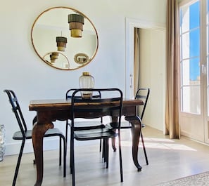A dining area with a wooden table, black chairs, a round mirror, and a hanging light fixture. - Diamond Suite Luxury Penthouse (Granada)