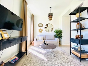 Ein modernes Wohnzimmer mit einem Flachbildfernseher, einem Sofa, einem Couchtisch und einem Bücherregal.