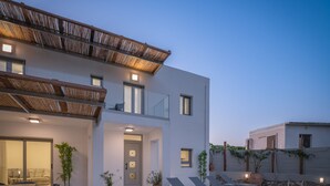 A modern two-story house with a swimming pool, outdoor seating, and potted plants.