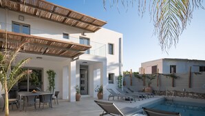 A modern house with a pool, outdoor seating, and a pergola.