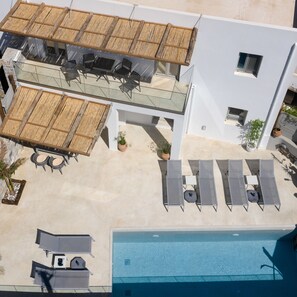 Una terrazza panoramica con piscina, poltroncine relax e zona pranzo con tavoli e sedie.