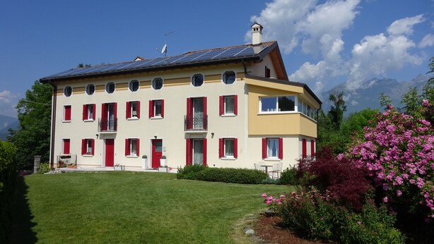 Un edificio ampio su due piani, con molte finestre, un balcone e pannelli solari sul tetto.