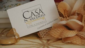 Un letto e un libro intitolato "Casa N'Vecento", con particolare attenzione a camere e appartamenti.