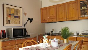 Cucina con pensili in legno, un forno a microonde, una macchina da caffè e un tavolo da pranzo per due persone.