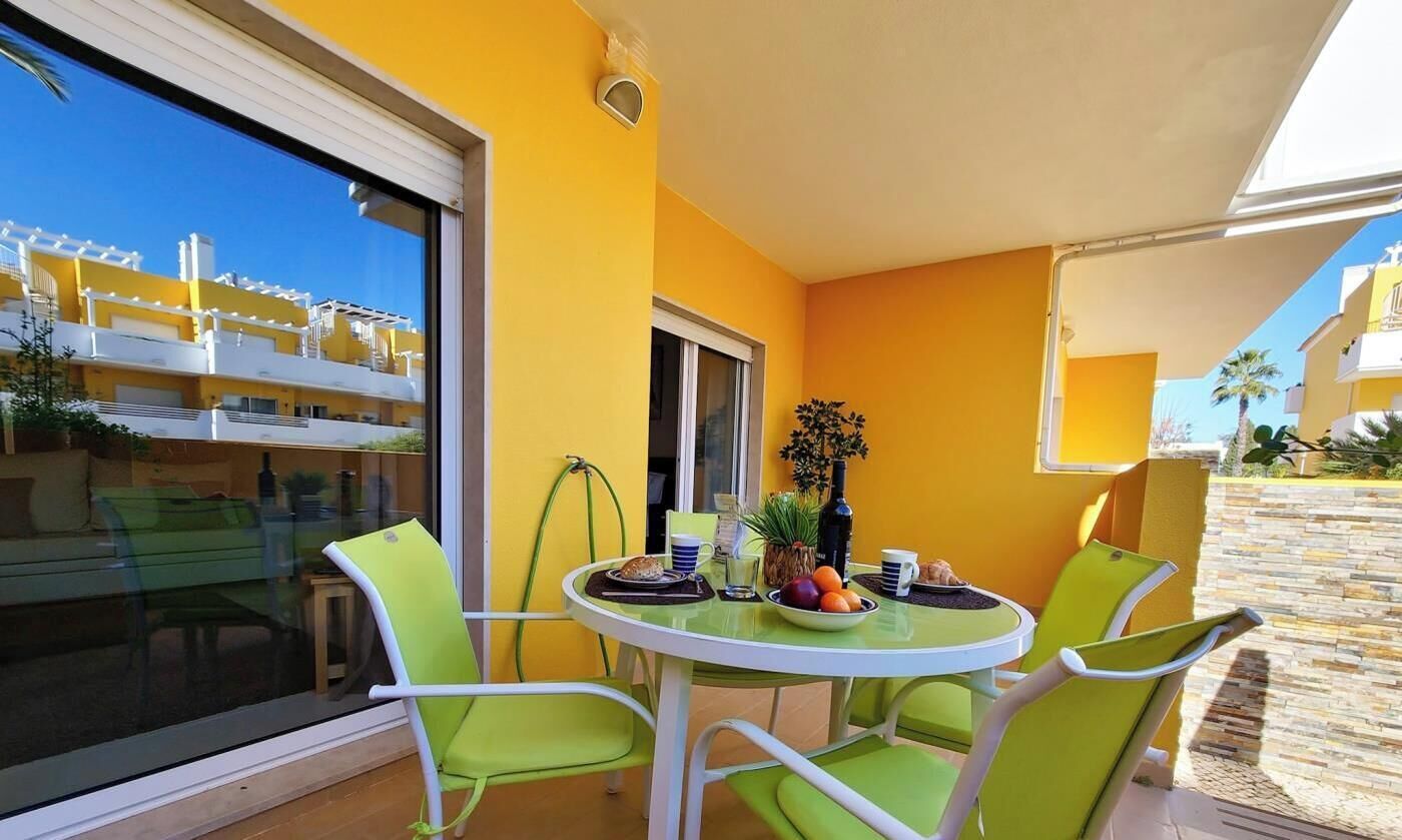A balcony with a round table, two chairs, and a small potted plant.