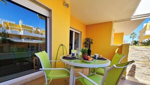 Ein Balkon mit rundem Tisch, zwei Stühlen und einem kleinen Blumentopf.