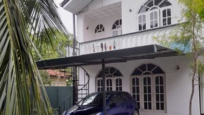 Un bâtiment à deux étages avec une voiture garée dans l’allée.