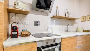 Una cocina moderna con horno empotrado, microondas y televisor de pantalla plana.