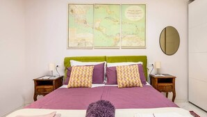Un dormitorio ordenado con una cama grande, dos mesitas de noche, un mapa en la pared y un espejo.