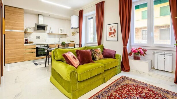 Una sala de estar moderna con un sofá verde, un comedor y una cocina.