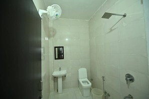 Un baño con inodoro, lavamanos, ducha y un ventilador.
