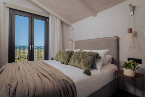A bedroom with a large bed, a nightstand, a potted plant, and a view of the outdoors through a sliding door.