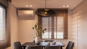 Ein moderner Essbereich mit einem rechteckigen Tisch, vier grauen Stühlen, einer dekorativen Vase mit Pflanzen und einer außergewöhnlichen Hängeleuchte.