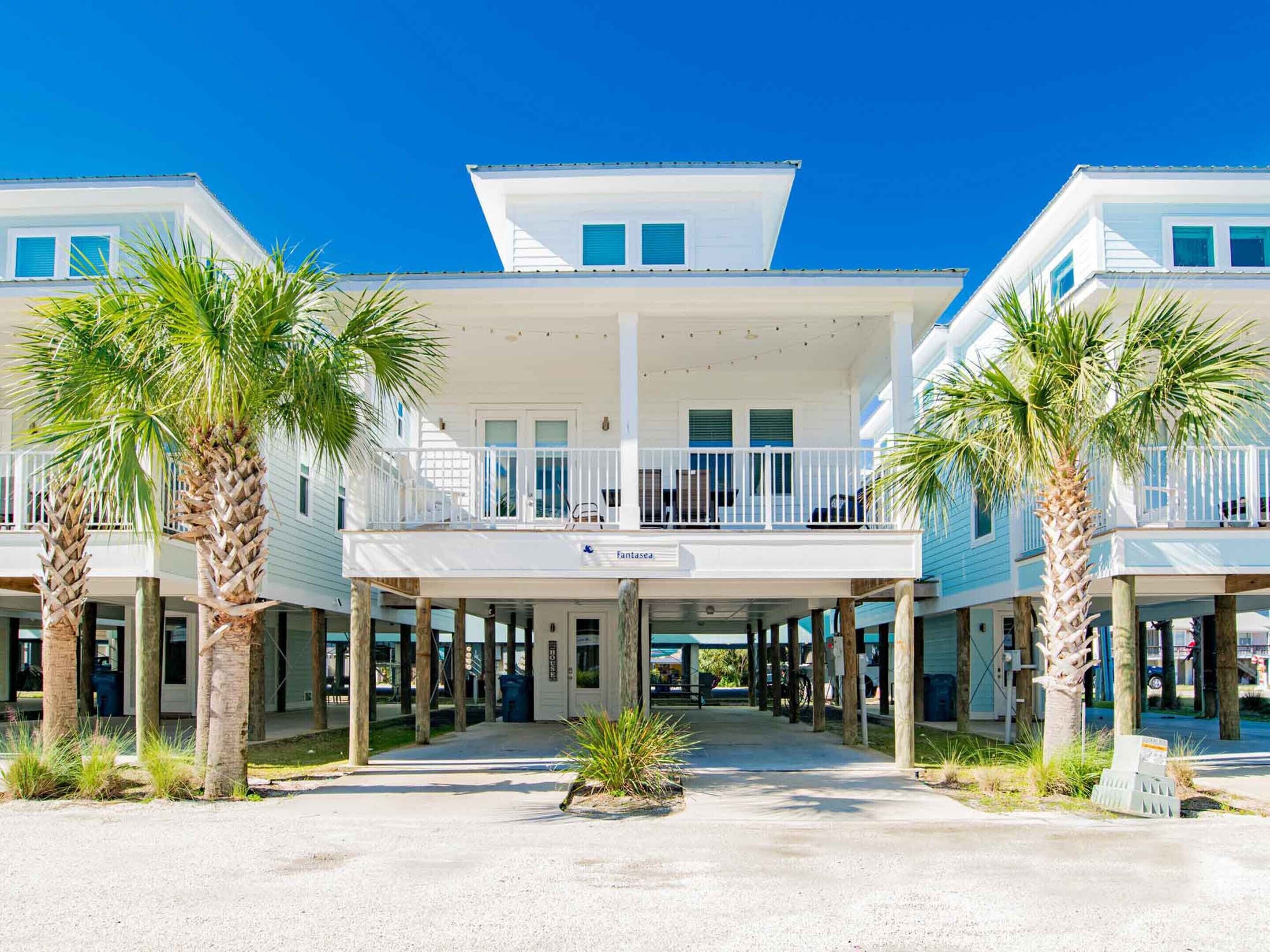 A beachfront hotel with a central courtyard, multiple balconies, and palm trees.