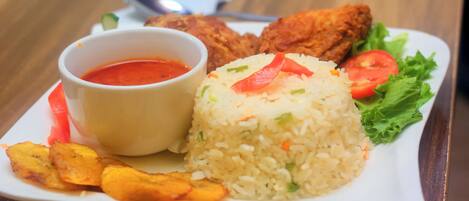 A plate of food with rice, fried chicken, and a small bowl of sauce.