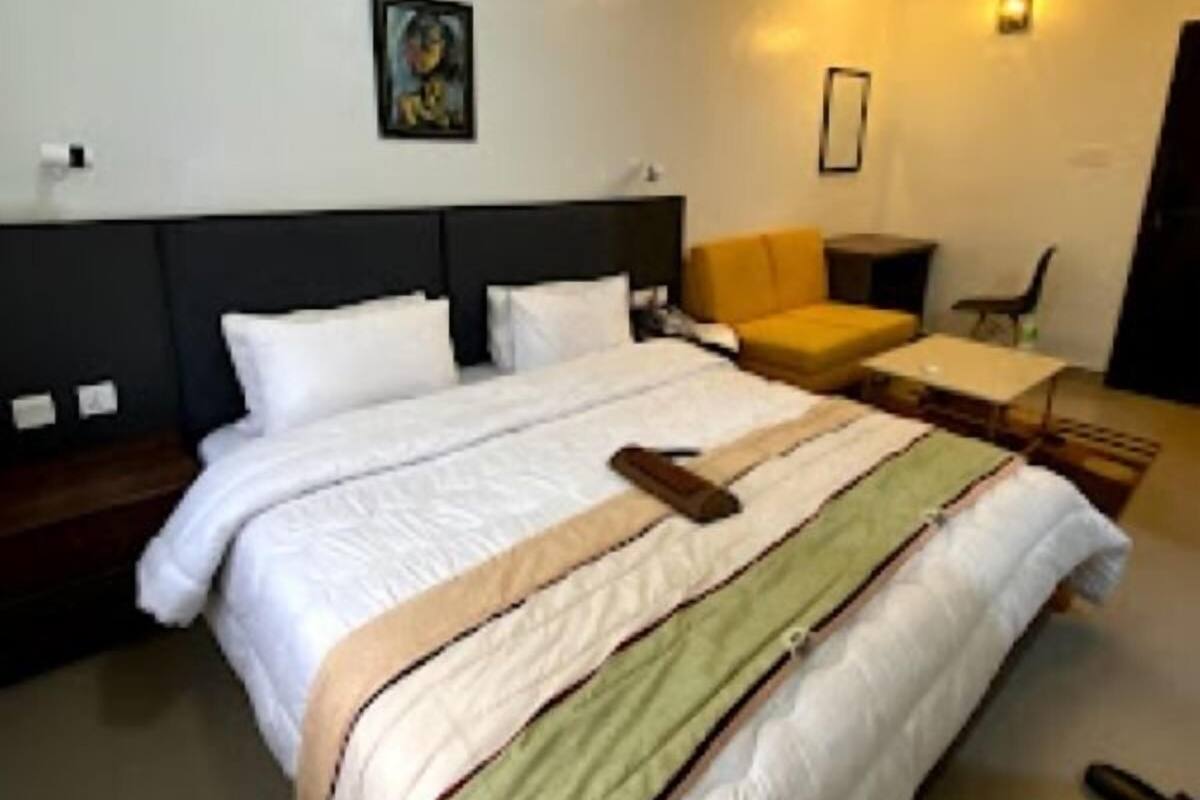 A modern hotel room with a large bed, a bedside table, a chair, and a small table.