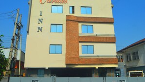 Un immeuble à plusieurs étages portant l’enseigne « Caritas INN », ce qui indique qu’il s’agit d’un hôtel.