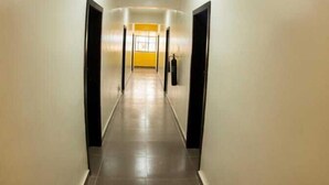 Un long couloir étroit, doté d’un sol carrelé et de murs sobres.