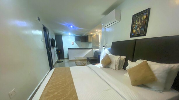 Une chambre d’hôtel avec un lit, une table de chevet, un bureau et une chaise. Il y a une fenêtre et un appareil de climatisation fixé au mur.