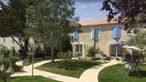 A courtyard with a stone building, a paved walkway, and outdoor furniture. - Plume 4* charming gites with swimming pool, golf practice and children's playground (Chambon)