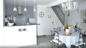A modern kitchen with a central island, pendant lights, and a dining area with a chandelier. - Plume 4* charming gites with swimming pool, golf practice and children's playground (Chambon)