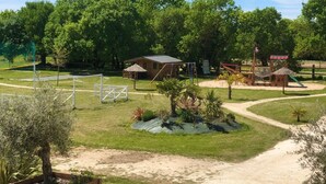 A playground with a swing set, a small hut, and a fenced area. - Plume 4* charming gites with swimming pool, golf practice and children's playground (Chambon)
