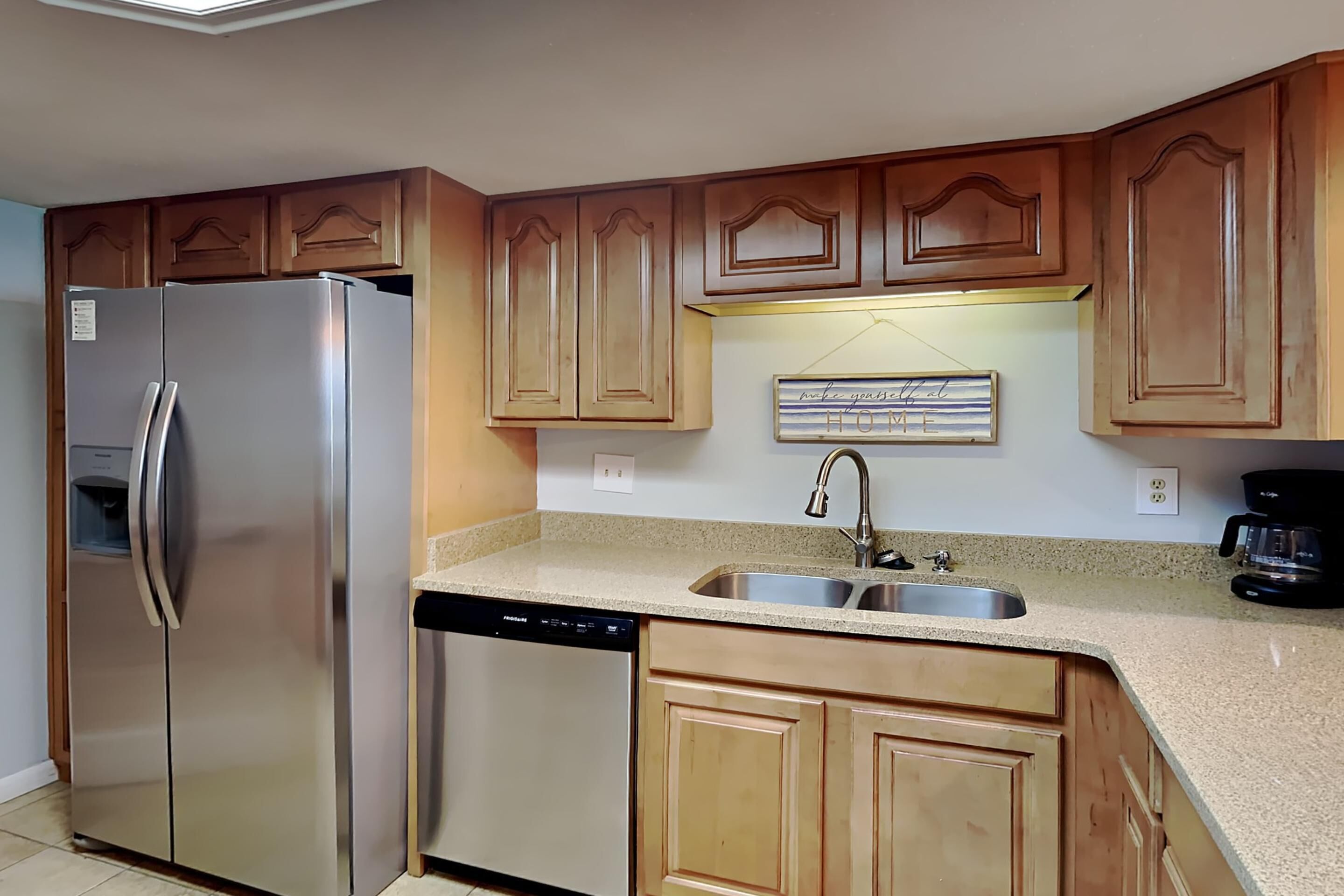 A kitchen with wooden cabinets, stainless steel appliances, a dishwasher, and a double sink.
