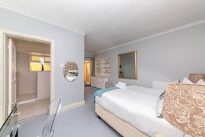 A bedroom with a bed, a mirror, a wardrobe, and a door leading to another room.