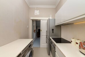 A compact kitchen with a washing machine, a refrigerator, and a stove.